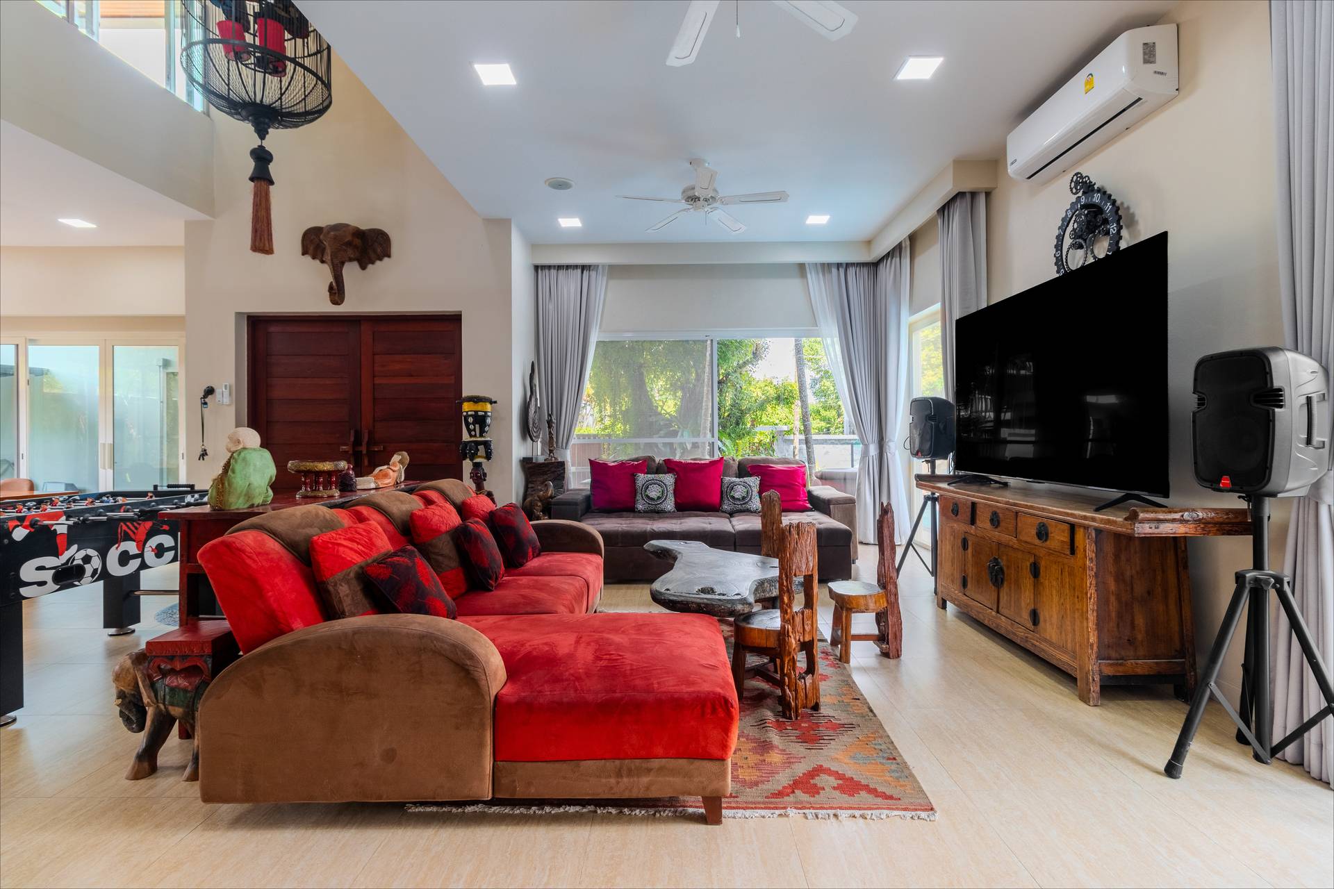 Open-plan living area with plush sofas, large TV, and traditional Asian furnishings