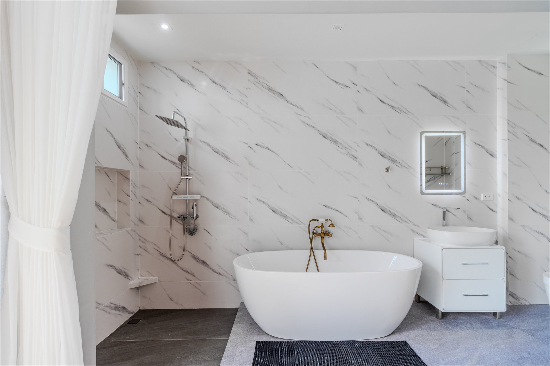 Luxurious en-suite bathroom with freestanding soaking tub, rain shower, and white marble walls