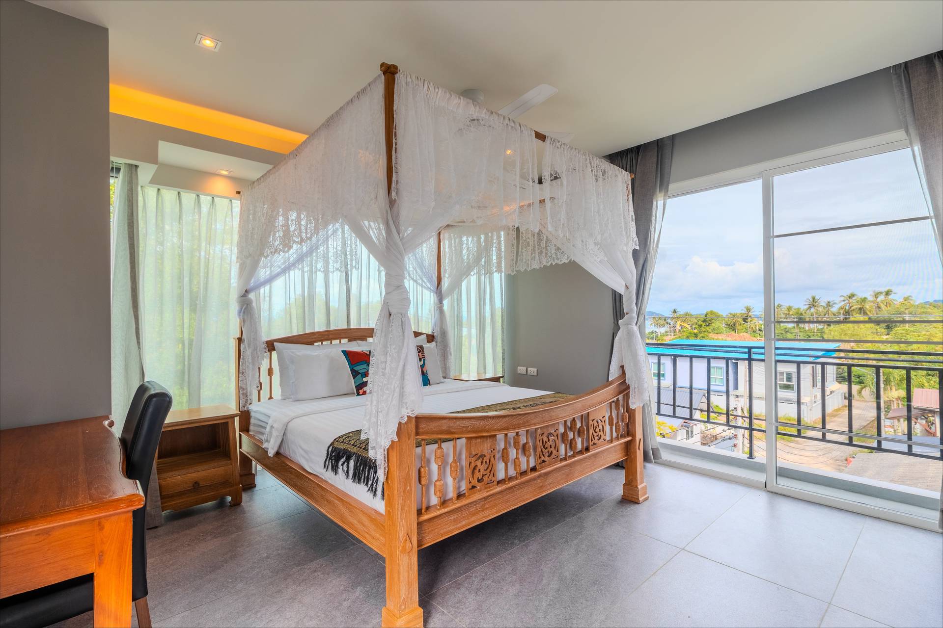 Airy four-poster canopy bedroom with panoramic views, desk area, and lace draping