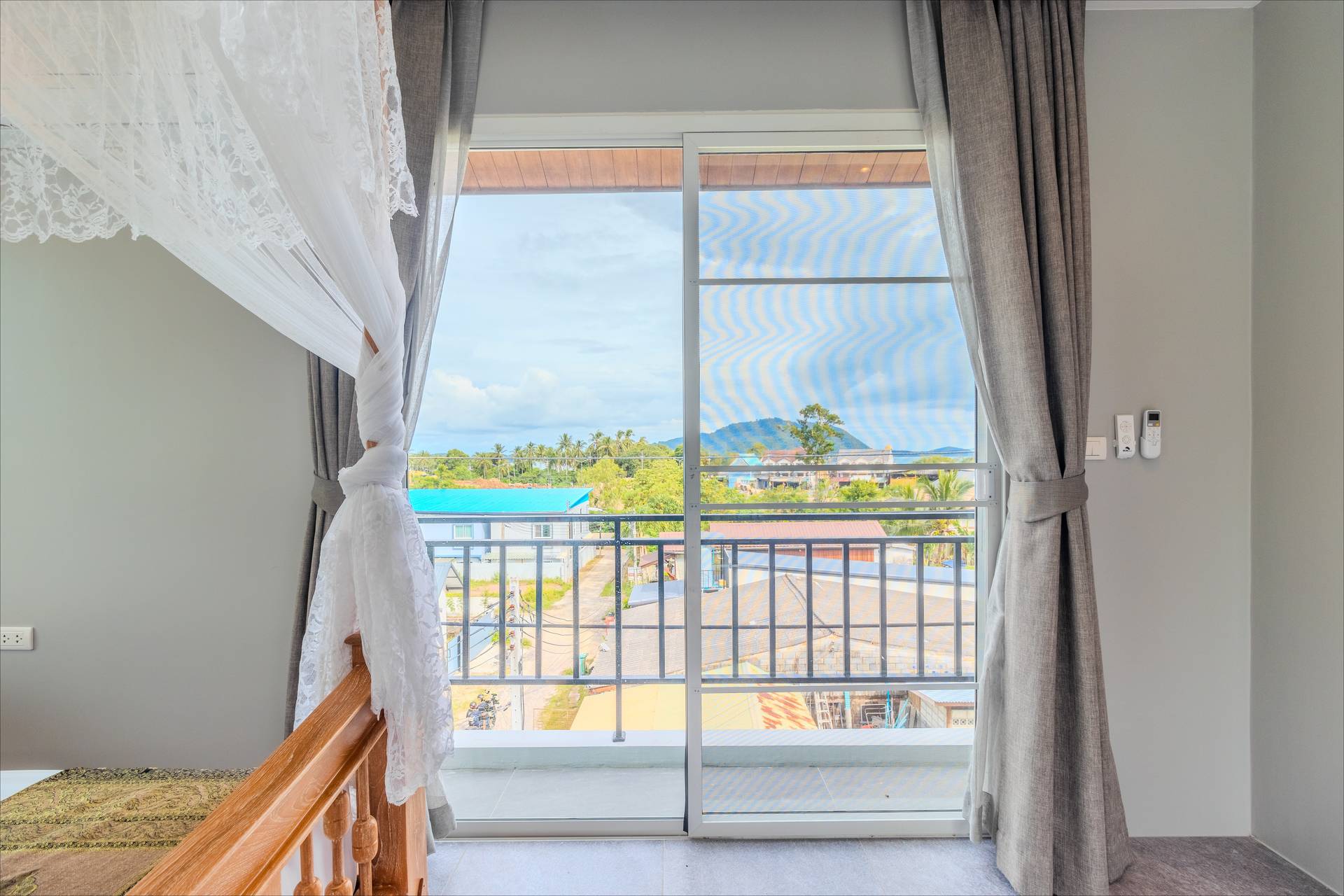 Bedroom balcony view of Rawai hills and palm trees through floor-to-ceiling sliding doors