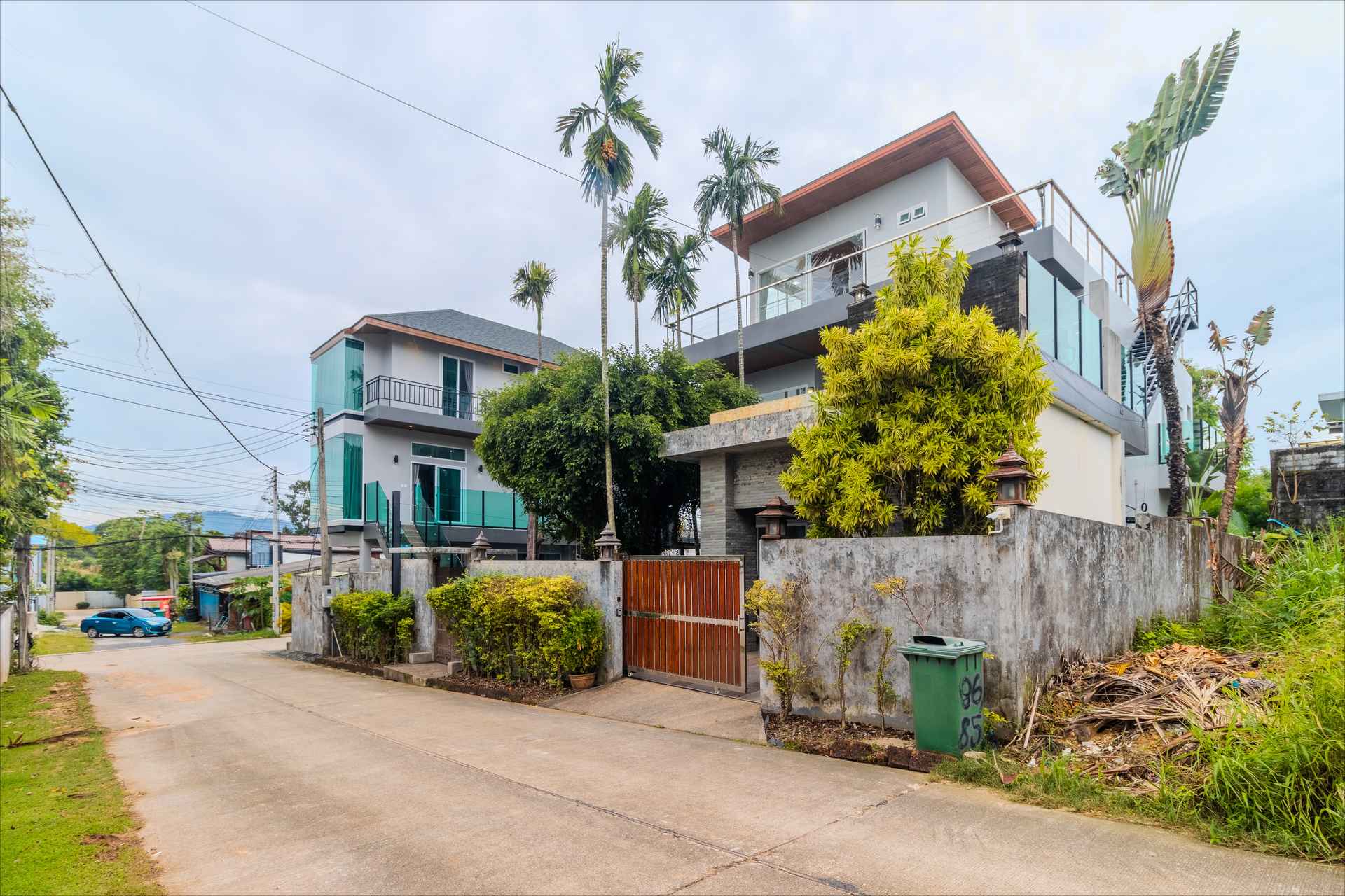 Front facade of 10-bedroom Phuket villa complex with tropical landscaping and gated entrance