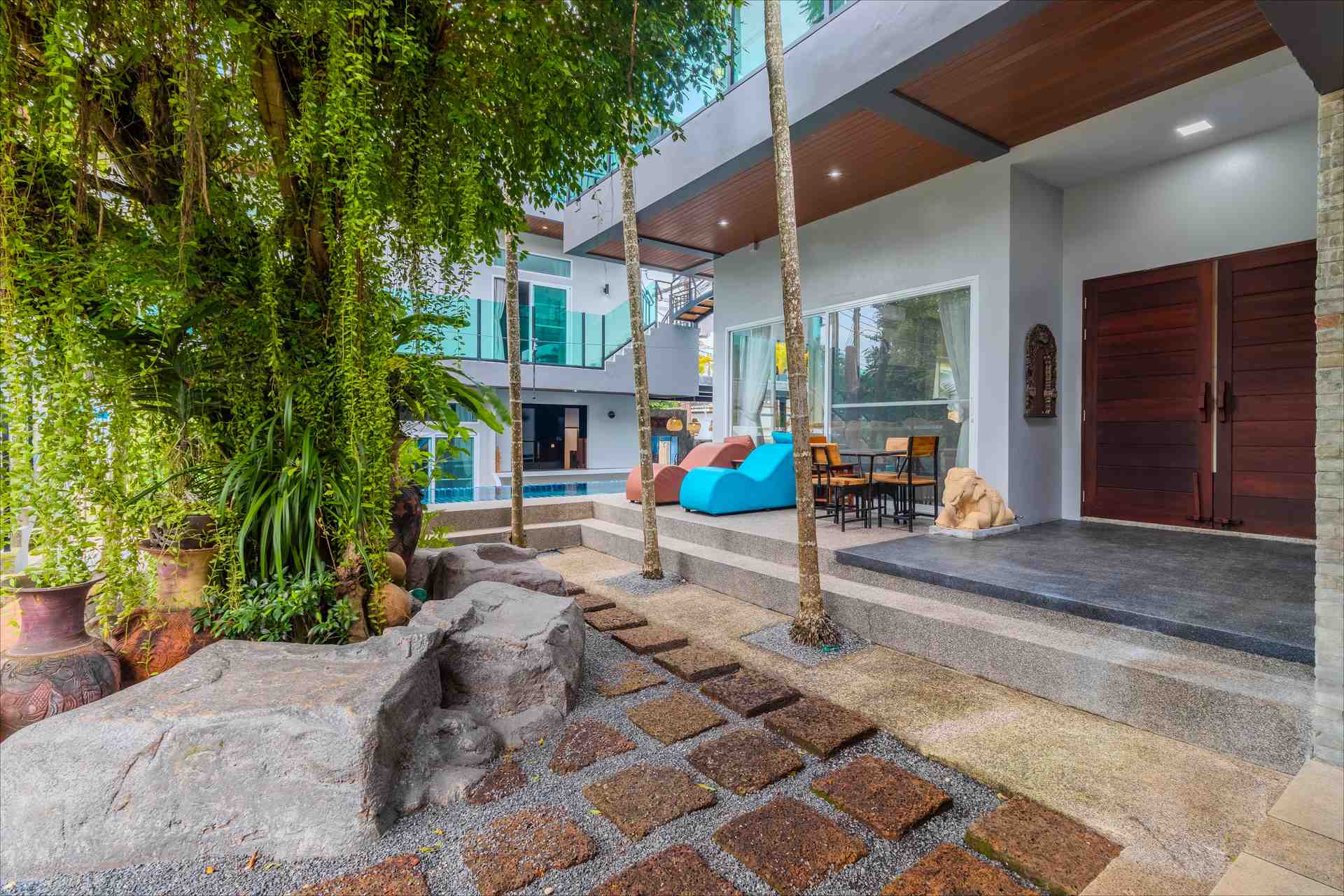 Villa courtyard entrance with stone pathway, tropical plants, and traditional elephant sculptures