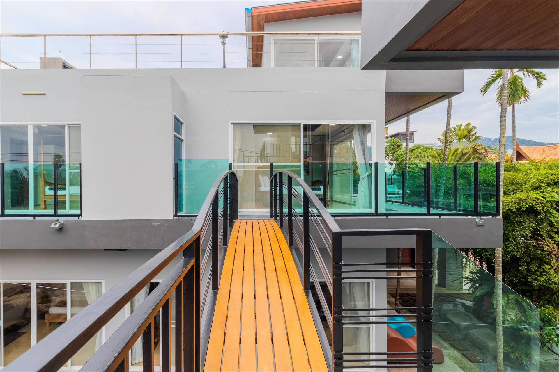 Elevated wooden sky bridge connecting villa buildings with panoramic tropical views