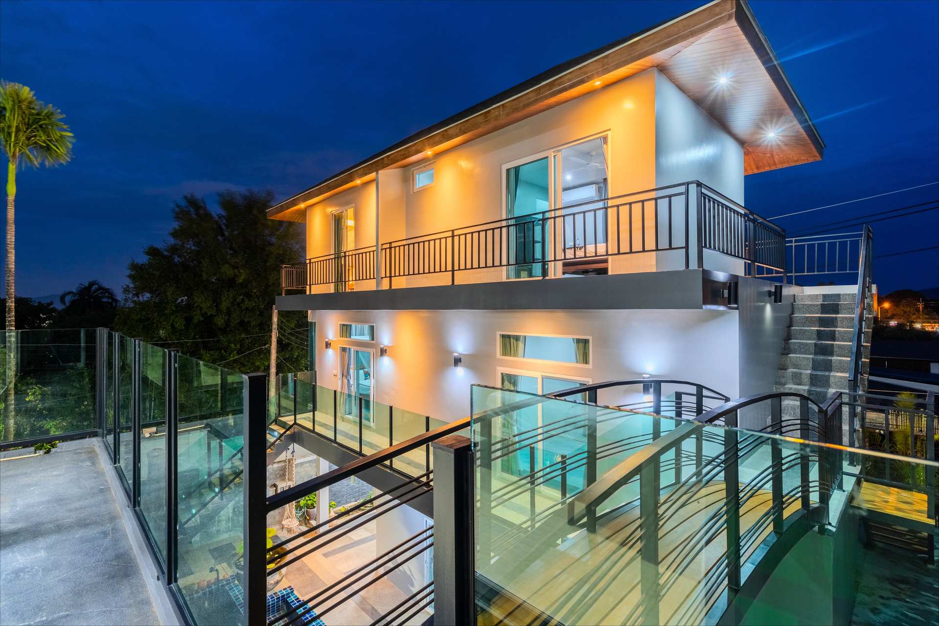 Panoramic view of the villa entrance with tropical landscaping and grand driveway