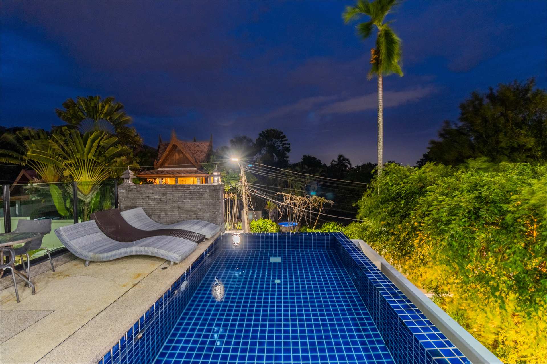 Upper-level walkway and balcony overlooking villa courtyard and pool at dusk